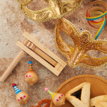 Purim celebration concept. Jewish carnival background. hamantaschen or hamans ears cookies, carnival mask and noisemaker.