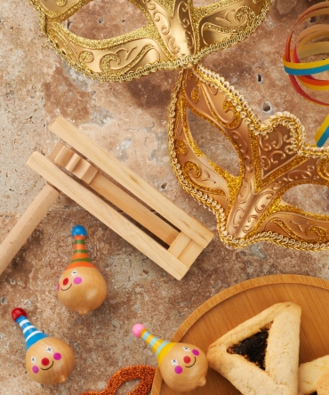 Purim celebration concept. Jewish carnival background. hamantaschen or hamans ears cookies, carnival mask and noisemaker.